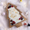 Holiday candle in a wooden Christmas tree bowl, featuring cranberry and fir like decor with a warm ambiance.